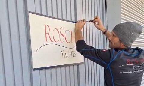 RoSch-Mitarbeiter demontiert Firmenschild an Halle.